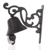 Decorative cast iron bell attached to an intricately designed wall bracket with scroll details and a hanging clapper.